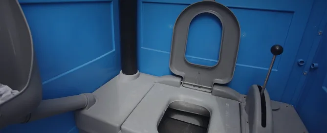 Inside a blue and gray porta potty with the seat open - Common Bizarre and Disgusting Things Found in Porta Potties - ServiceCore Blog