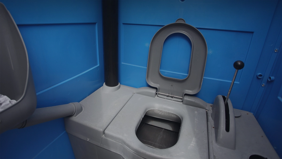 Inside a blue and gray porta potty with the seat open - Common Bizarre and Disgusting Things Found in Porta Potties - ServiceCore Blog