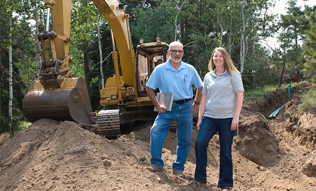 septic tank owners standing in front of construction | what you'll need to run a septic system business | ServiceCore software for portable restroom & dumpster companies”