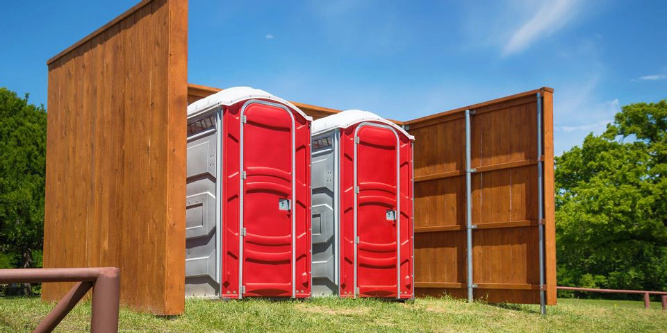 Red porta potties fenced in - Types of Insurance Portable Restroom Operators Need - ServiceCore Blog