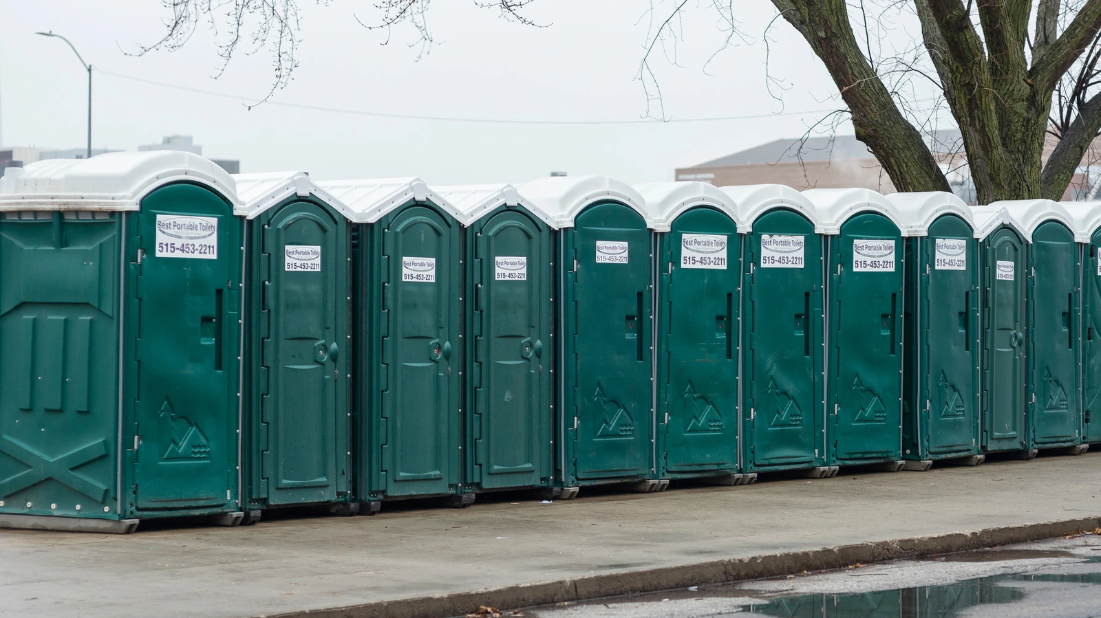 Long row of green portable toilet units - History of the Porta Potty - ServiceCore Blog