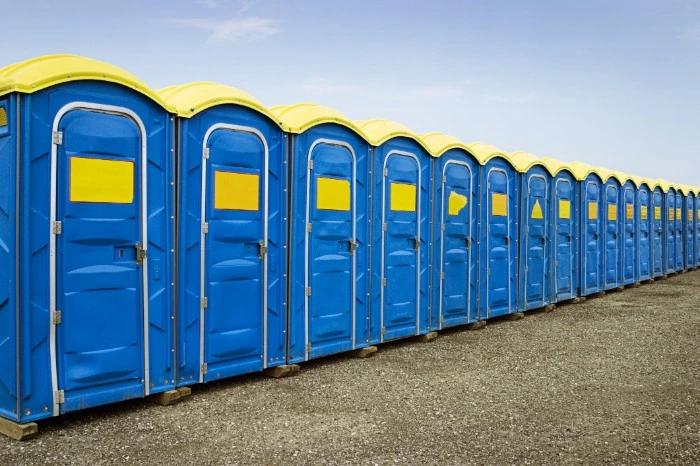 Row of blue and yellow porta potties - Common Bizarre and Disgusting Things Found in Porta Potties - ServiceCore Blog