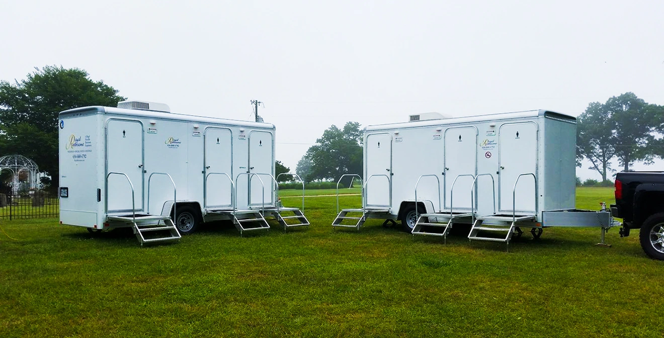 Two portable restroom trailers parked in the grass - The Only Guide You Need To Starting a Portable Restroom Business - ServiceCore Blog