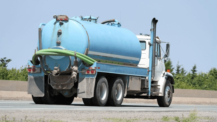 blue septic pump truck going down the road | start up costs for septic tank business | ServiceCore software for portable restroom & dumpster companies”