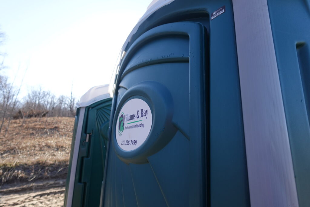 Close Up visual of green porta potty labelled with the William's and Bay Pumping company logo