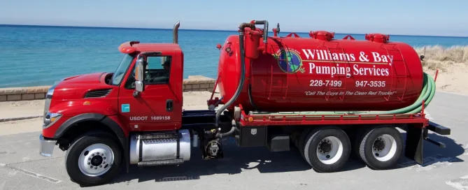 Red Williams & Bay pumping service truck parked next to the waterfront on a cloudless day