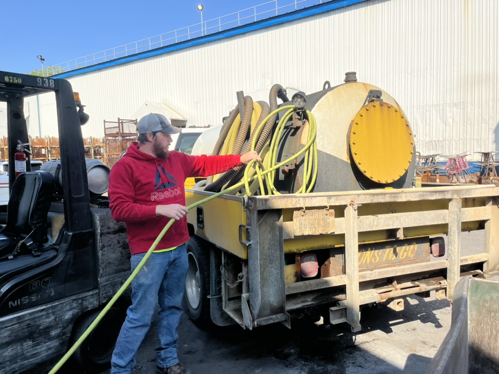 Male porta pottyvoperator unhooking water hose on a portable sanitation truck in Michigan.